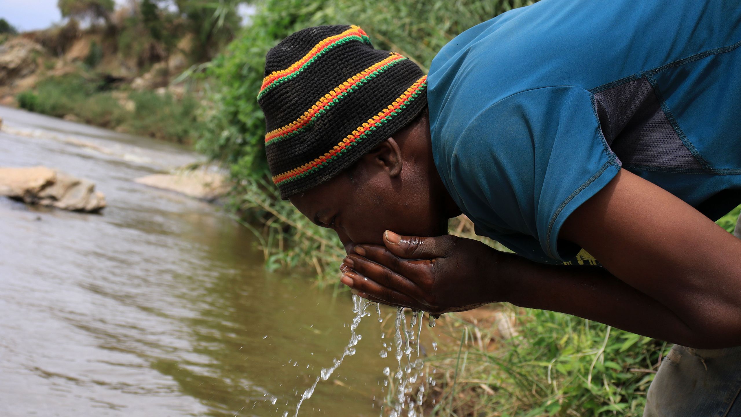 A man drinks water from Athi River in Thwake, Makueni.